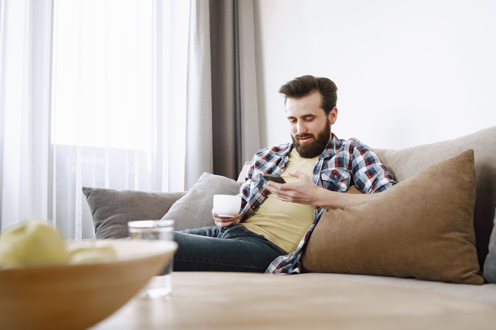 Man on couch with phone and coffee